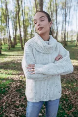 Sweater tejido en punto inglés color crudo con chispas de colores y cuello alto ancho.