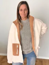 Campera de tejido tipo borrego color crudo, con detalles en pana color camel en bolsillo y cuello interior. De corte oversize y fit relajado, con cierre frontal de cremallera y bolsillos funcionales.