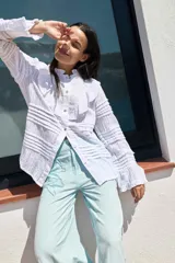 Camisa blanca de algodón con cuello mao, volados en el frente y mangas largas con puños abotonados.