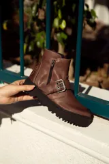 Bota de cuero color marrón con cierre lateral y detalle de hebilla.