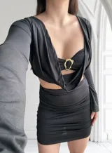 Vestido negro de tres piezas, compuesto por un top tipo corpiño con aro dorado, una falda mini fruncida y un cardigan de mangas largas.