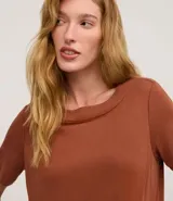 Vestido corto marrón, estilo camiseta, con escote redondo, mangas cortas y bolsillos laterales. El bajo es redondeado.