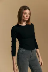 Remera blanca de manga larga con tejido acanalado, cuello redondo y corte ajustado al cuerpo. Presenta costuras verticales que definen la silueta.