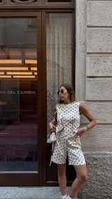 Blusa blanca con lunares negros, cruzada y atada en la cintura. Sin mangas y con cuello en V.