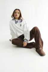 Buzo celeste con cuello polo y puños en rib color verde lima. Tiene un parche con el logo de la marca en el pecho y rayas horizontales en el ruedo.