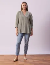 Blusa verde con rayas verticales blancas, cuello a la base y escote en V con aplique de botones. Manga ¾ con puño y botón. Tajo en costuras laterales.