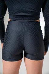 Calza corta deportiva negra con estampado de líneas onduladas que simulan el pelaje de una cebra.