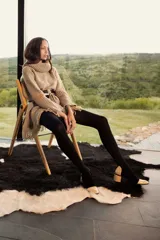 Poncho de tejido grueso color beige, con cuello alto y flecos en el ruedo.