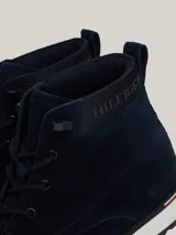 Botines Tommy Hilfiger de hombre, color azul marino, confeccionados en ante con interior de poliéster y suela de goma. Presentan cordones, logo Hilfiger en el tobillo y detalle distintivo en el talón.