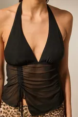 Top negro sin mangas con cuello halter profundo, frunces ajustables en el frente y diseño transparente en la parte inferior.