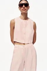 Pantalón de vestir color rosa pálido, de tiro alto, con pinzas delanteras, bolsillos laterales, pierna ancha y cierre frontal con cremallera y botón.