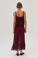 Falda midi tejida color bordó, con flecos y calados en el bajo.