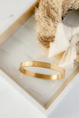 Brazalete rígido de acero color oro rosa con números romanos grabados.