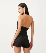 Mono corto negro de sastrería en crepé, con escote halter cruzado, busto marcado y abertura en el abdomen.