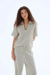 Top de punto con textura a rayas horizontales en blanco y negro. Tiene cuello camisero abierto, mangas cortas y corte holgado.
