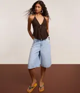 Bermuda tipo jorts de jeans, tiro medio/alto, color celeste claro lavado, corte ancho y largo que llega por encima de la rodilla. Presenta cinco bolsillos y trabillas para cinturón.