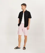 Bermuda de hombre de corte recto, confeccionada en tejido plano de lino y algodón. Diseño liso en color rosado con textura discreta, cintura con trabillas para cinturón, cierre frontal de botón y cremallera, y bolsillos laterales.