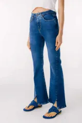 Pantalón de jean azul de corte acampanado con aberturas en el ruedo.