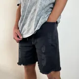 Bermuda de jean negro con roturas y terminación desflecada.