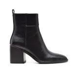 Botas de cuero negro con caña media, punta cuadrada y taco geométrico. Presentan un tirador trasero y elástico lateral para facilitar el calce.