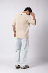 Camisa negra tejida de manga corta, con calado aireado, cuello tipo bowling y botones al tono. Diseño de corte relajado.