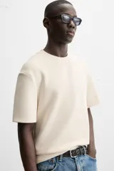 Camiseta de hombre de corte relaxed fit, confeccionada en tejido de algodón compacto con estructura piqué. Presenta cuello redondo y mangas cortas.