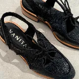 Zapato tipo sueco de cuero vacuno negro con textura reptil, con cordones y talón descubierto. Tiene suela de madera con altura de 4,5 cm en el talón y 1,5 cm en la parte delantera.