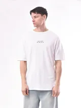 Remera blanca de corte holgado con estampado pequeño en el pecho que dice 'SIGHT+SOUND' y símbolos de audio.