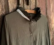 Camisa oversize color verde musgo, con cuello alto con volados y detalle de puntilla blanca.