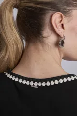 Remera negra ajustada al cuerpo, tipo musculosa, con escote redondo y ribetes en blanco con apliques de perlas en el contorno del cuello y las sisas.