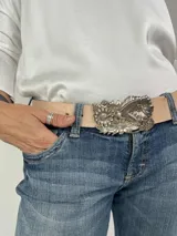 Cinturón de cuero color beige con hebilla metálica plateada con diseño de flores y colibrí.