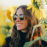 Lentes de sol con montura de madera clara con vetas marrones y lentes grises degradadas.