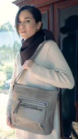 Bandolera beige de símil cuero con dos bolsillos frontales con cierre, un bolsillo trasero, tres bolsillos internos y correa larga regulable.