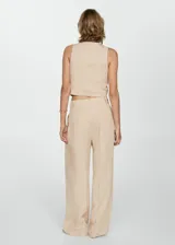 Pantalón de vestir color beige, de corte wide leg, tiro medio, con pinzas delanteras y cierre frontal con botón, gancho y cremallera.