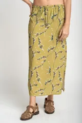Falda midi color verde oliva con estampado de ramas y hojas en tonos grises y blancos. Tiene cintura elastizada con cordón ajustable y un tajo lateral.
