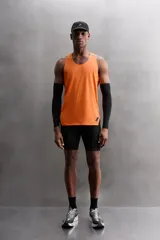 Camiseta deportiva sin mangas color beige, confeccionada en tejido técnico ligero y elástico con estructura perforada. Tiene cuello redondo amplio, sisas con acabados termofijados, bajo con aberturas laterales y logo estampado.