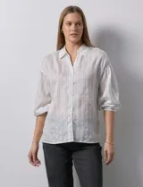 Camisa texturada blanca con líneas verticales negras, marca Hester & Orchard. Cuello a la base, escote en V y abertura central con botones. Manga ¾ con terminación fruncida.