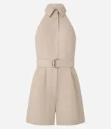 Mono corto color beige, con cuello halter tipo camisa, abotonado en el frente y cinturón con hebilla metálica.