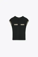 Camiseta negra de corte slim fit, cuello redondo y manga corta. Presenta falsos bolsillos en el delantero y detalle de hilo metalizado en mangas y bolsillos.