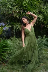 Vestido largo verde oliva de gasa, con escote en V, breteles finos y falda con volados escalonados.