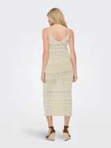 Vestido largo tejido color crudo, con escote en V, breteles finos y diseño calado.