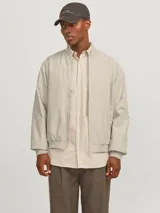 Campera bomber color beige de Jack & Jones, con cuello baseball, cierre frontal con cremallera, bolsillos delanteros y puños de canalé.