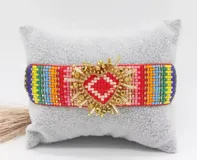 Set de pulseras tejidas con cuentas de colores y dije de corazón dorado.
