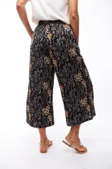 Pantalón capri negro con estampado abstracto en tonos beige, gris y marrón.