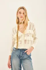 Cardigan color crema tejido en punto desagujado con volados tejidos en rib, calce crop y silueta ancha.