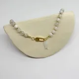 Collar elaborado con cuentas de Piedra de la Luna de 8 mm de diámetro, separadas por nuditos de hilo color caramelo. El cierre es de acero hipoalergénico con baño dorado y tiene un dije de nácar en forma de pez.