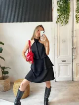 Minivestido negro con escote halter con detalle de flor, corte escalonado y falda corta.