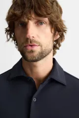 Camisa azul marino slim fit de manga larga con cuello italiano abierto y cierre frontal con botones.