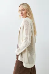 Ruana color beige claro con flecos en el borde inferior.