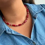 Collar corto de cuentas rojas con forma de barril alternadas con cuentas plateadas redondas.